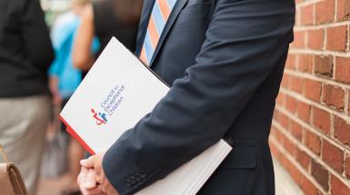 Man in suit holding a CEC document