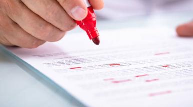 Close-up image of someone reading a document with a red marker in hand